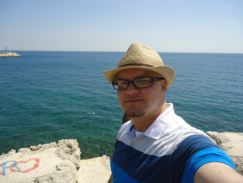 Pedro Gabriel by the sea, wearing a straw hat and glasses